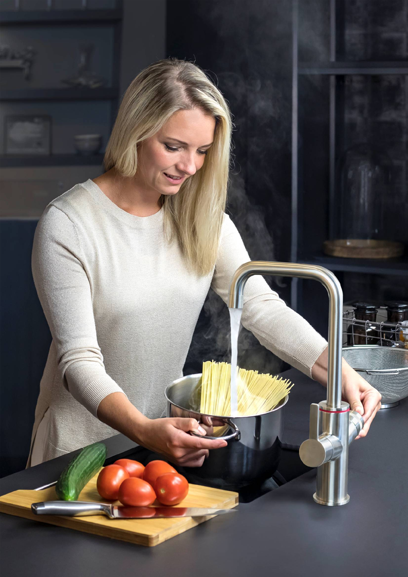 Vrouw kookt pasta met kokend water uit een UNITO kraan, moderne 3-in-1 keuken kraan met direct kokend water.