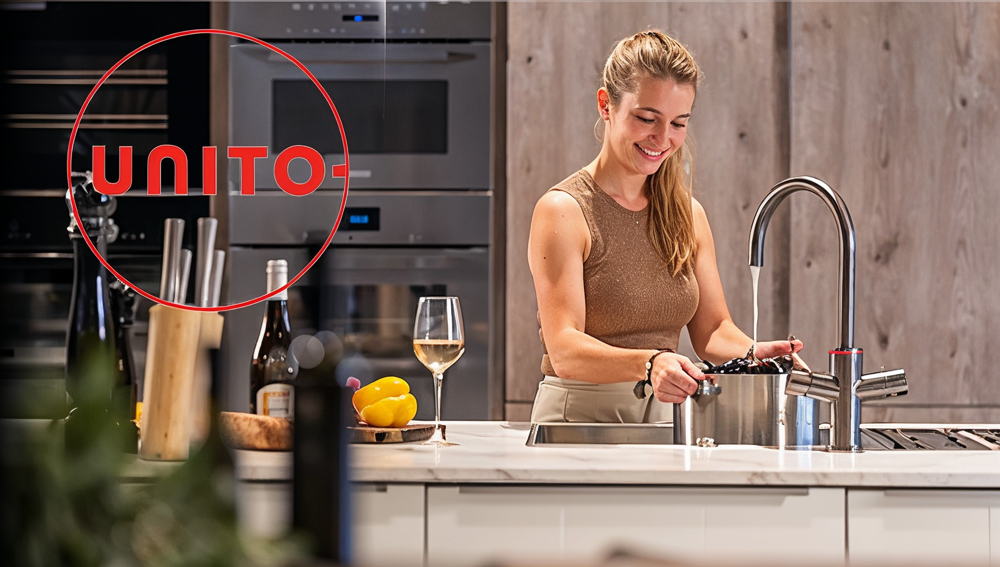 Vrouw vult pan met water uit Unito kokend water kraan in moderne keuken