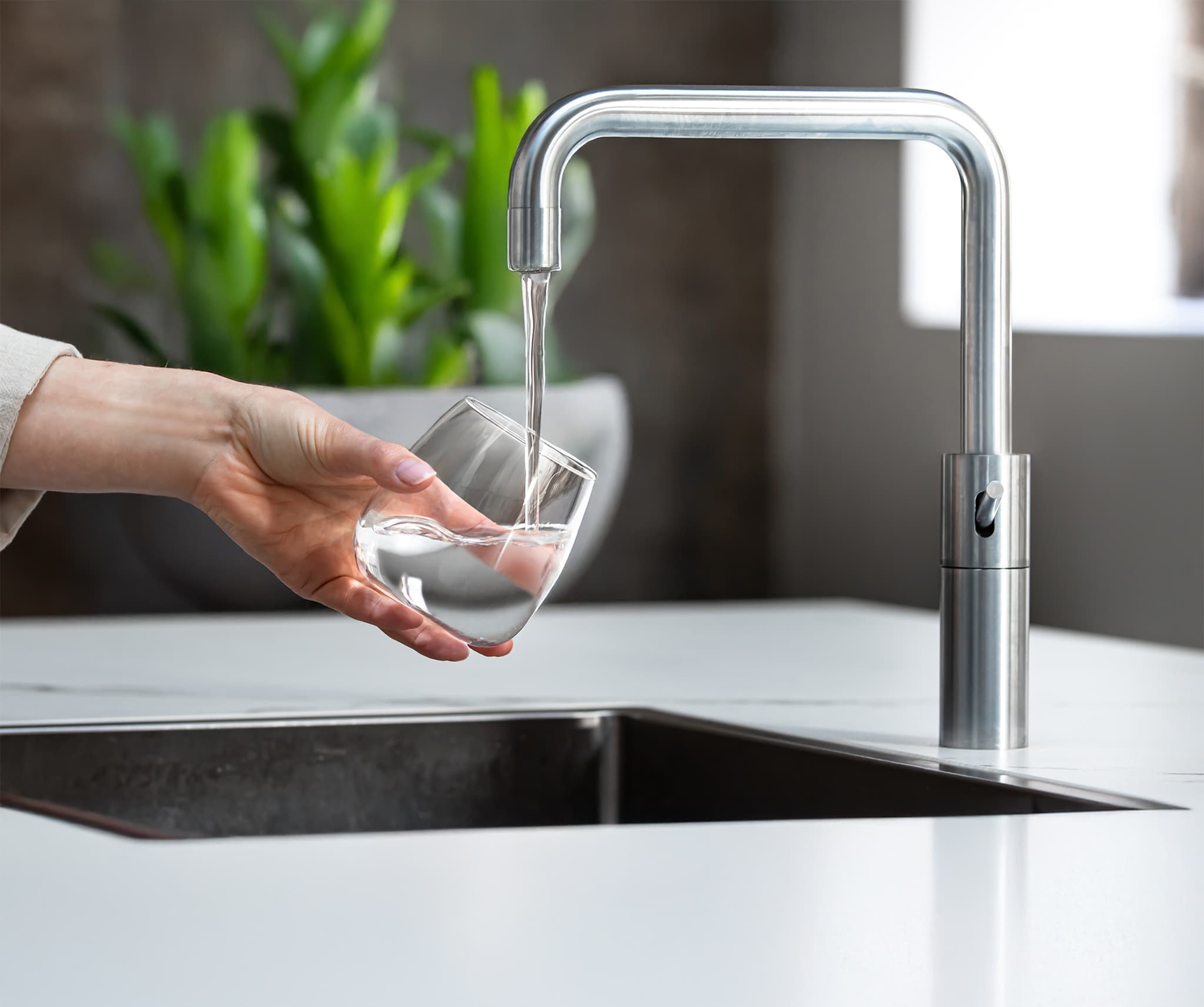 Vrouw vult glas met zuiver water uit keukenkraan aangesloten op reverse osmosis waterfilter