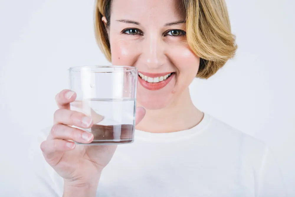 Vrouw met een glas water bij de uitleg over hard water en hoe werkt een waterontharder van PureAqua