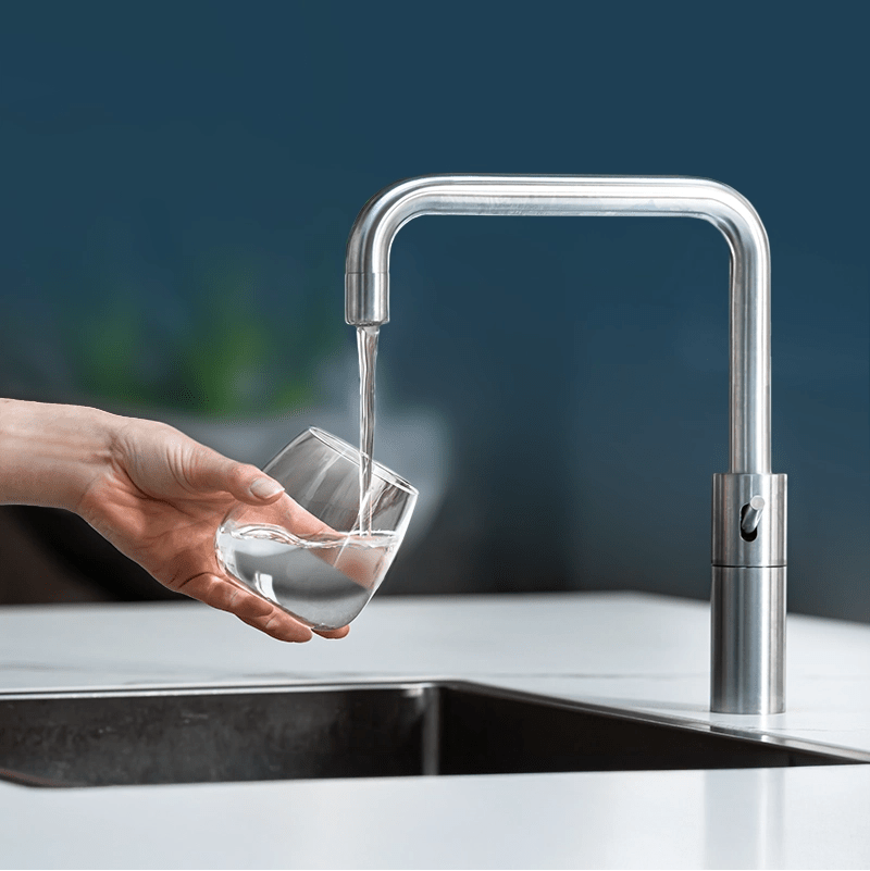 Zuiver water abonnement: hand vult glas met gefilterd water onder rvs keukenkraan | PureAqua