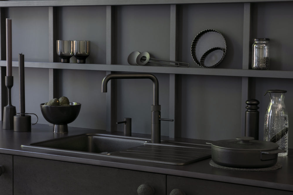 Zwarte Quooker kokendwaterkraan in een moderne designkeuken met donkere tinten en stijlvolle accessoires
